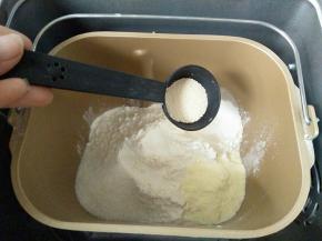 倒入面粉、奶粉，尽量盖住牛奶液，在一角放入细砂糖，另一角放酵母，保证糖与酵母不能直接接触，按下揉面程序
