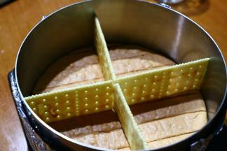 用慕斯模具按压出底一片蛋糕片铺底，模具底部要包上两层锡纸，再入在一个平的盘子上，这样方便挪动且不易漏，再用四苏打饼干十字形隔开。