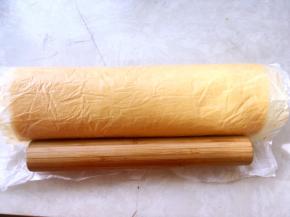 擀面杖将底下的油纸反向卷起，将蛋糕卷卷起来