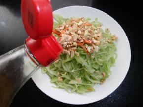 拌好的萝卜丝放入盘中。加上一些花生碎和青红椒。淋上一些香油。