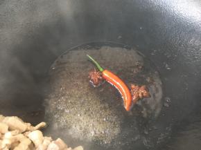 将肉丁扒在锅的一边或者盛出备用都可以。用煸炒出的底油，煸香八角和辣椒。