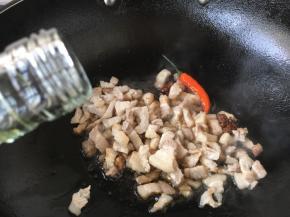 然后放入肉丁，煸炒均匀，沿锅沿烹入1勺的料酒。