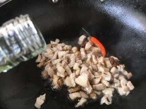 然后放入肉丁，煸炒均匀，沿锅沿烹入1勺的料酒。