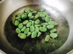蚕豆可提前焯水，也可直接炒，焯水时一定要用开水焯水，水里放一点盐和两滴油，因为蚕豆很嫩，焯水时间不能过长，避免蚕豆太软，影响口感，水开后汆烫1分钟左右即可，捞出沥干水分备用。