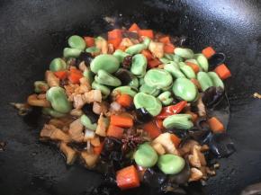 倒入蚕豆，继续翻炒至蚕豆熟。