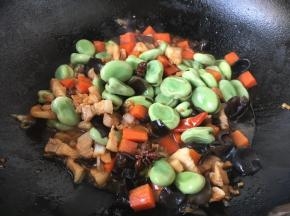 倒入蚕豆，继续翻炒至蚕豆熟。