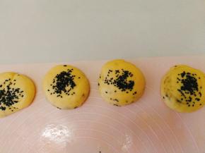 用手指抓适量黑芝麻，放在面饼上面。