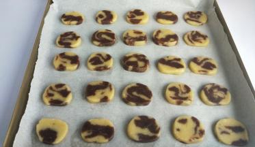 冷冻好的面团取出切薄片，放在铺好油纸的烤盘上。