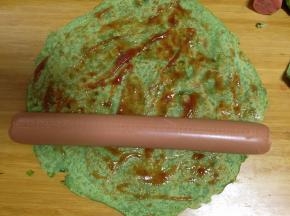 取一张蛋饼，涂上适量番茄沙司或是其它酱料，放入一根火腿肠