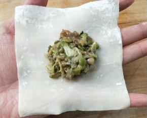 把槐花牛肉馅放馄饨皮中间。