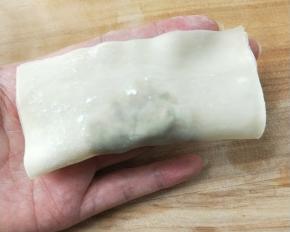 馄饨皮上方用手指头抹上一点水，对折捏紧。