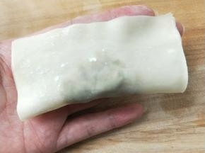 馄饨皮上方用手指头抹上一点水，对折捏紧。