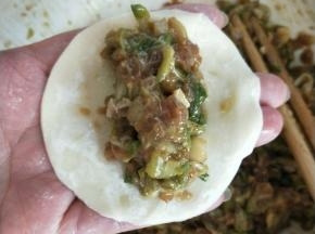 饺子皮一张，取槐花牛肉馅集中放饺子皮中间，用筷子夹一下肉馅边缘成长方形的感觉，饺子边最上方抹上一点水，对折捏紧中间，两边开口。
