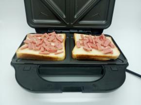 三明治机铺上牛奶吐司，喜欢吃原味的，可以放原味吐司，两边烤盘各放一片，撒上火腿肠，火腿肠铺的均匀一点