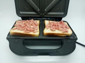 三明治机铺上牛奶吐司，喜欢吃原味的，可以放原味吐司，两边烤盘各放一片，撒上火腿肠，火腿肠铺的均匀一点
