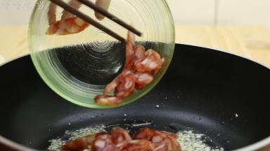 蒜末炒出香味后，加入腊肠，改中火，翻炒2分钟左右，把腊肠中的油适当的逼出来。