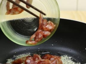 蒜末炒出香味后，加入腊肠，改中火，翻炒2分钟左右，把腊肠中的油适当的逼出来。