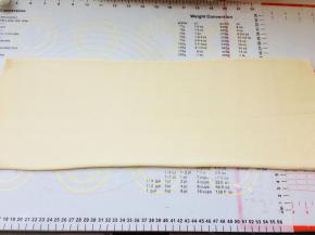 将面片旋转90度，也就是收口朝向左右。擀成长方形。修齐两端。擀时要从中间往两端擀，不可来回擀。