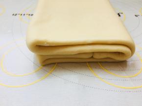 在沿着中心位置对折，完成第一次四折的折叠。包裹保鲜膜放入冰箱冷冻15到20分钟。