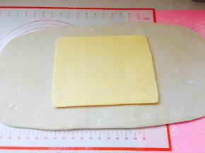 取出冷冻好的面团，将黄油片置于中间位置。轻按黄油片，让它与面之间更加服帖。