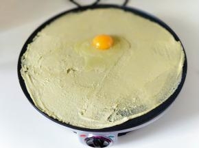 待面糊表面凝固时，敲一个鸡蛋。