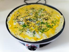 再撒上熟黑芝麻，待蛋液凝固后，把煎饼翻个面。
