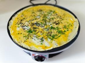 再撒上熟黑芝麻，待蛋液凝固后，把煎饼翻个面。
