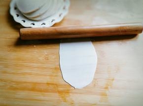 取一张饺子皮，用擀面杖擀出长舌状。