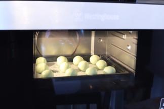 启动烤箱，放入装有青团的烤盘，开始蒸煮