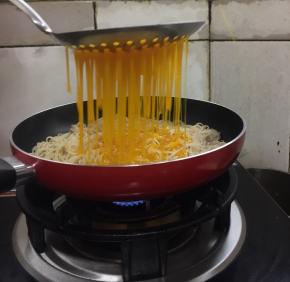 把搅拌好的蛋液用漏勺均匀的淋在面条上。