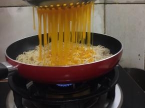 把搅拌好的蛋液用漏勺均匀的淋在面条上。