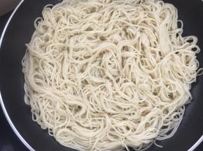 不粘平底锅烧热倒入适量的油，把煮好沥干水分的面条放入锅中小火煎制1分钟。