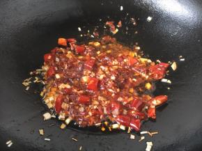 放入2勺的郫县豆瓣酱，煸炒1分钟左右，煸炒出红油。