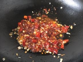 放入2勺的郫县豆瓣酱，煸炒1分钟左右，煸炒出红油。
