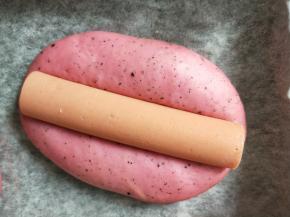 火腿肠去头尾，切成两半，放在发酵好的面团中间。