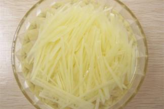 焯熟的土豆丝放入凉开水中冲洗。