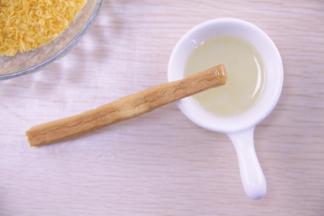 把烤好的花枝棒前端沾上蜂蜜，滚上面包糠，