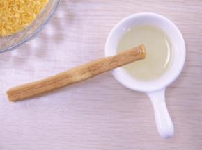 把烤好的花枝棒前端沾上蜂蜜，滚上面包糠，