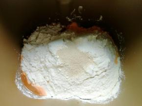 红萝卜汁倒进面包机桶，再放入300克面粉，2.5克酵母，开启揉面模式