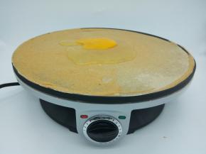 等面糊定型后，打一个鸡蛋在煎饼中间