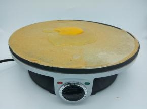 等面糊定型后，打一个鸡蛋在煎饼中间