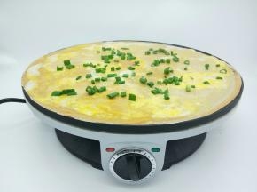 用木推将鸡蛋的蛋黄敲一下碎，再往煎饼四周摊开，撒点葱花