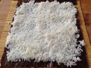 把米饭平铺在上面压实，注意尾部留出一点不要铺