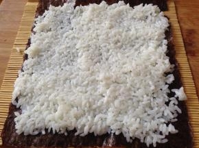把米饭平铺在上面压实，注意尾部留出一点不要铺
