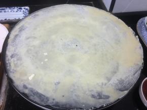 倒入两汤勺面糊，用面棍打圈摊匀。