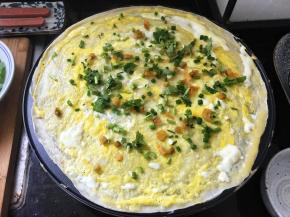 等蛋液表面凝固的差不多的时候，撒上香菜、葱花和榨菜。