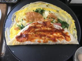 这时，将煎饼的一边对折一下，抹上蒜蓉甜面酱。