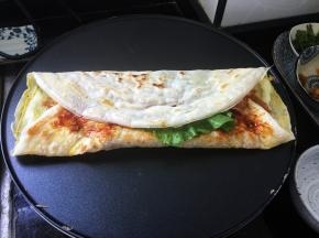 盖上一片生菜叶，顺着卷起来，杂粮煎饼就做好了。