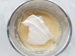 [混合蛋黄糊和蛋白霜]取三分之一蛋白霜加入蛋黄糊中，用手动打蛋器拌匀。