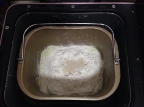 除去主面团里的椰子油和蔓越莓干，面包机桶底部加入液体原料，上面加入高粉、低粉和酵母，入面包机启动和面程序20分钟